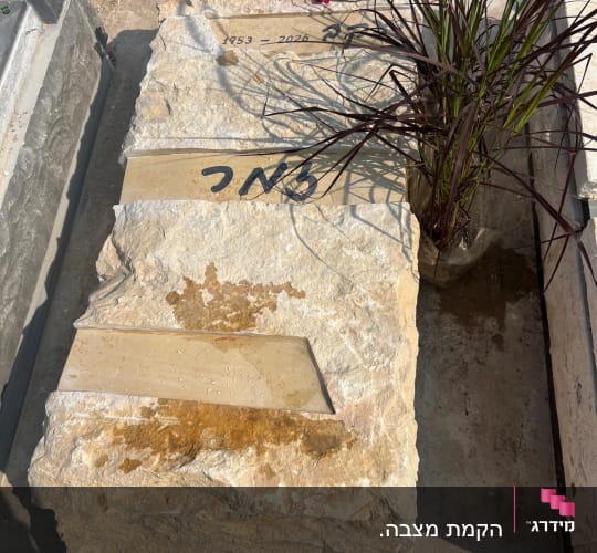 מצבה עם פרחים ואבן גדולה
